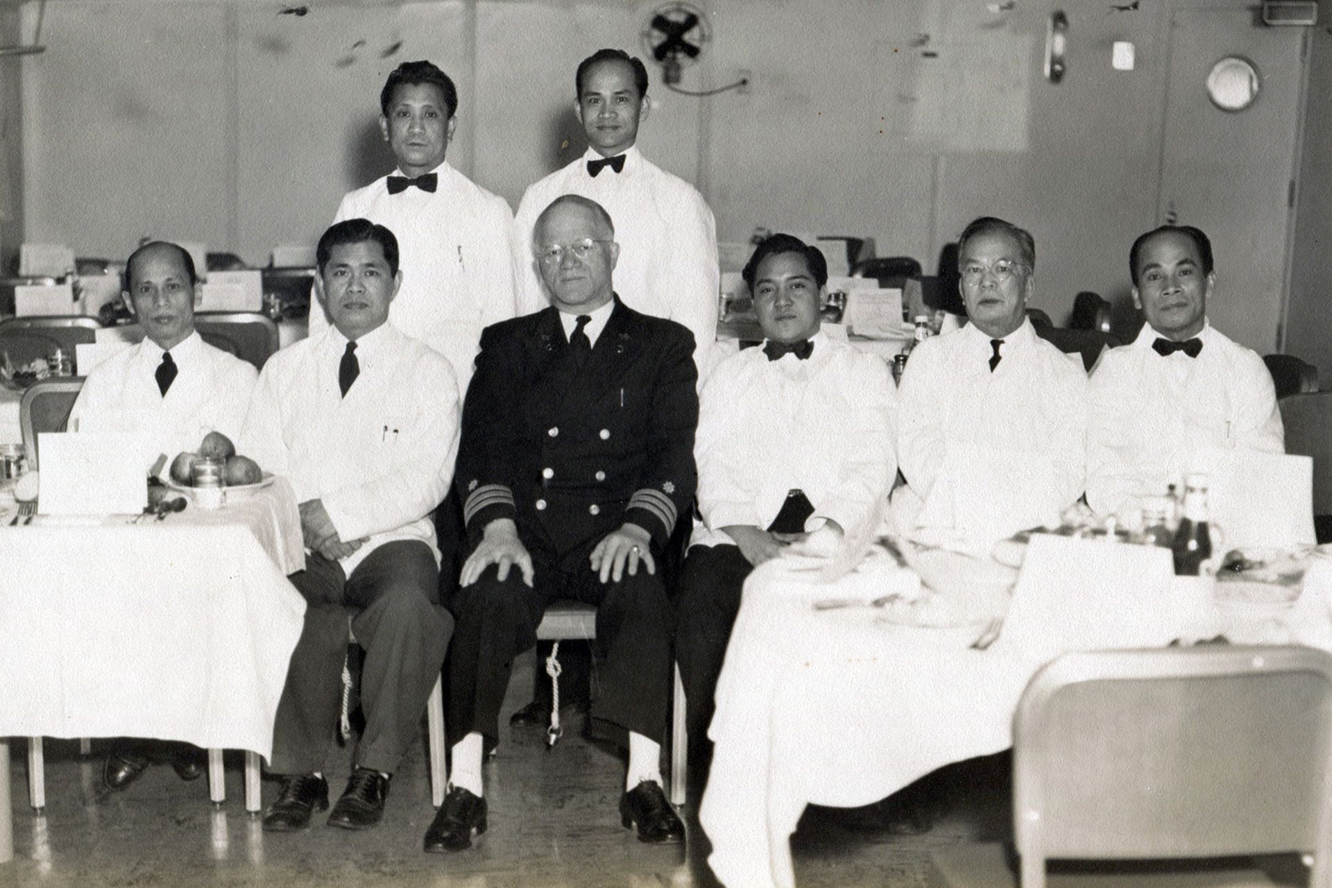 A black and white photo of a group of men standing on a pier