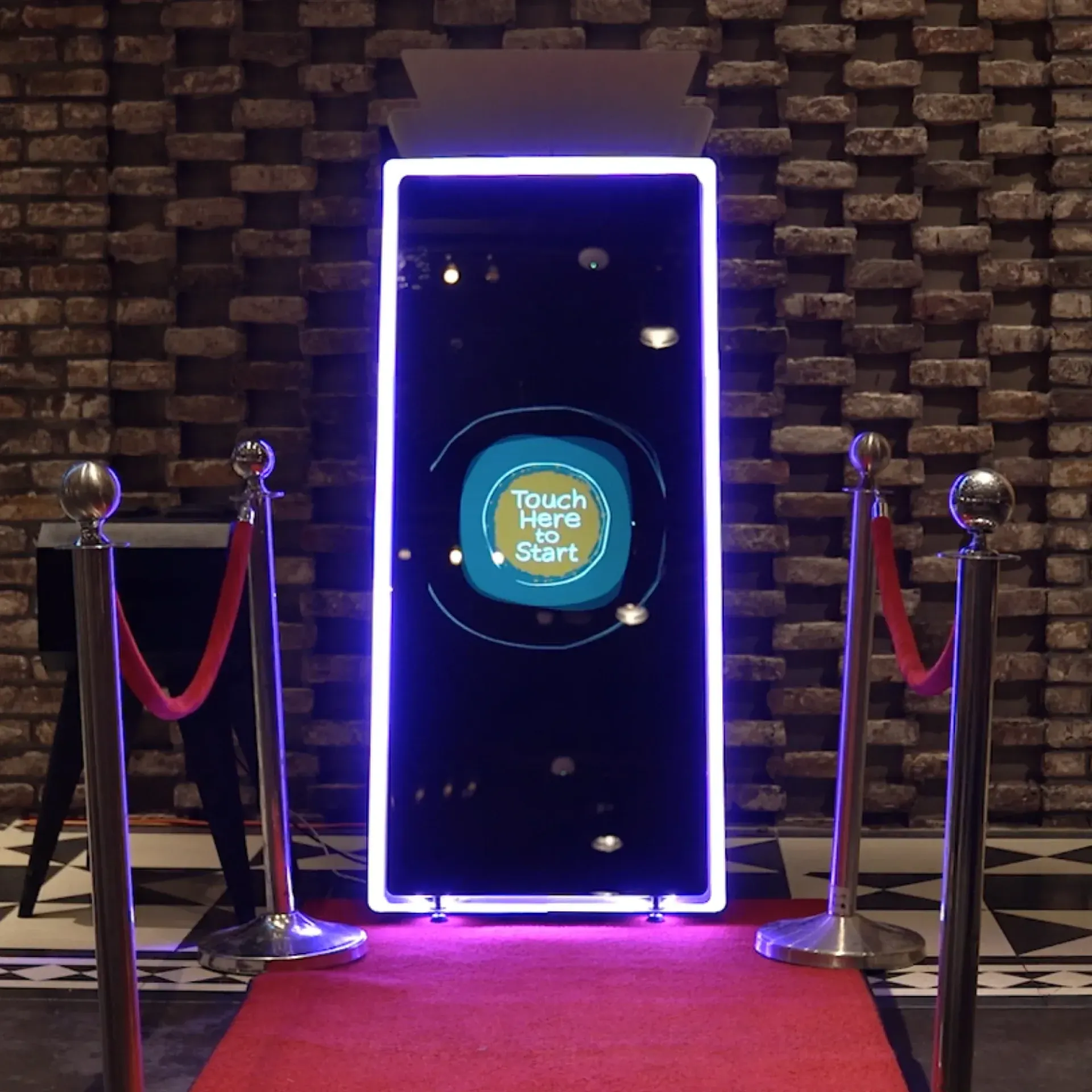 A photo booth with a sign that says touch here to start