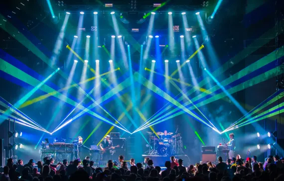 A crowd of people are watching a band on stage at a concert.