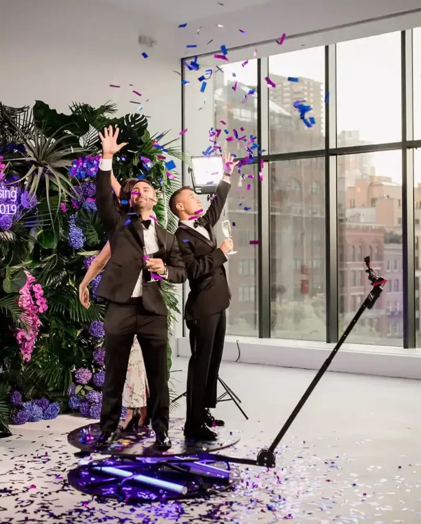 Two men in suits are standing next to each other in a room with confetti falling from the ceiling.
