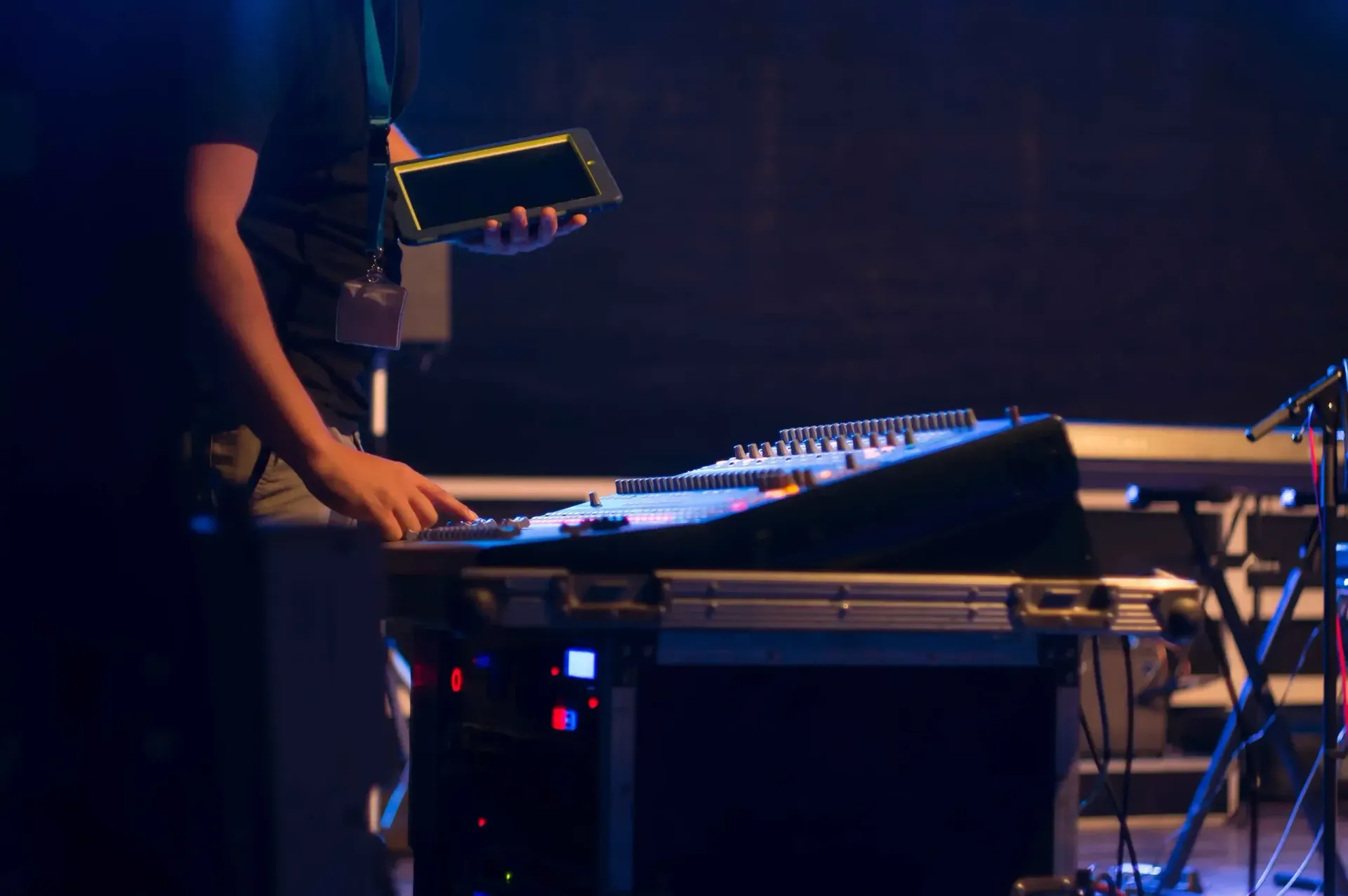A man is standing in front of a mixer on a stage holding a tablet.