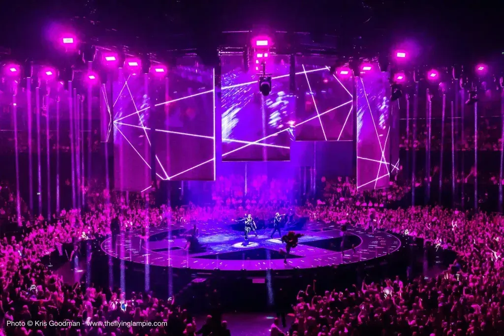 A crowd of people are watching a concert with purple lights
