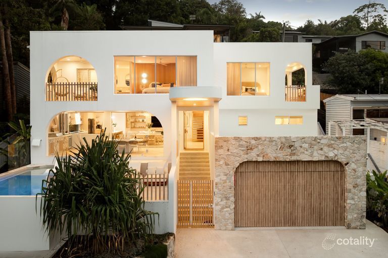 White modern house with arches, a pool, and a stone garage door.