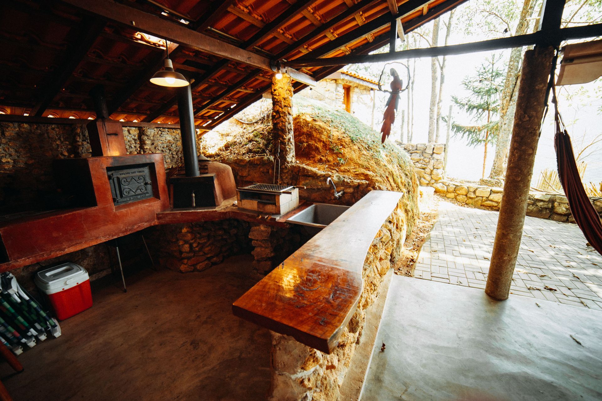 Rustic open-air cabin with wooden tables, stone stove, and snowy outdoor view