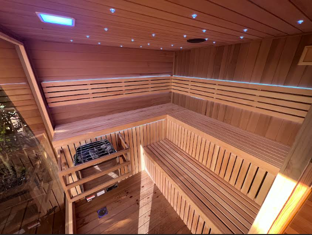 Wooden sauna interior with multiple tiered benches and a heater.