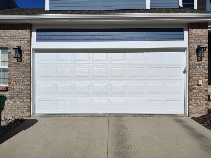 White double garage door on a brick house with a driveway in front