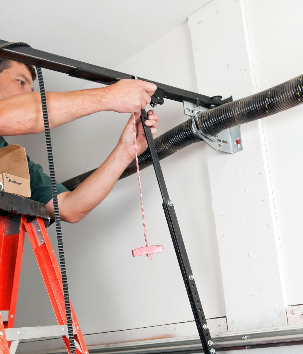 A man is standing on a ladder working on a garage door