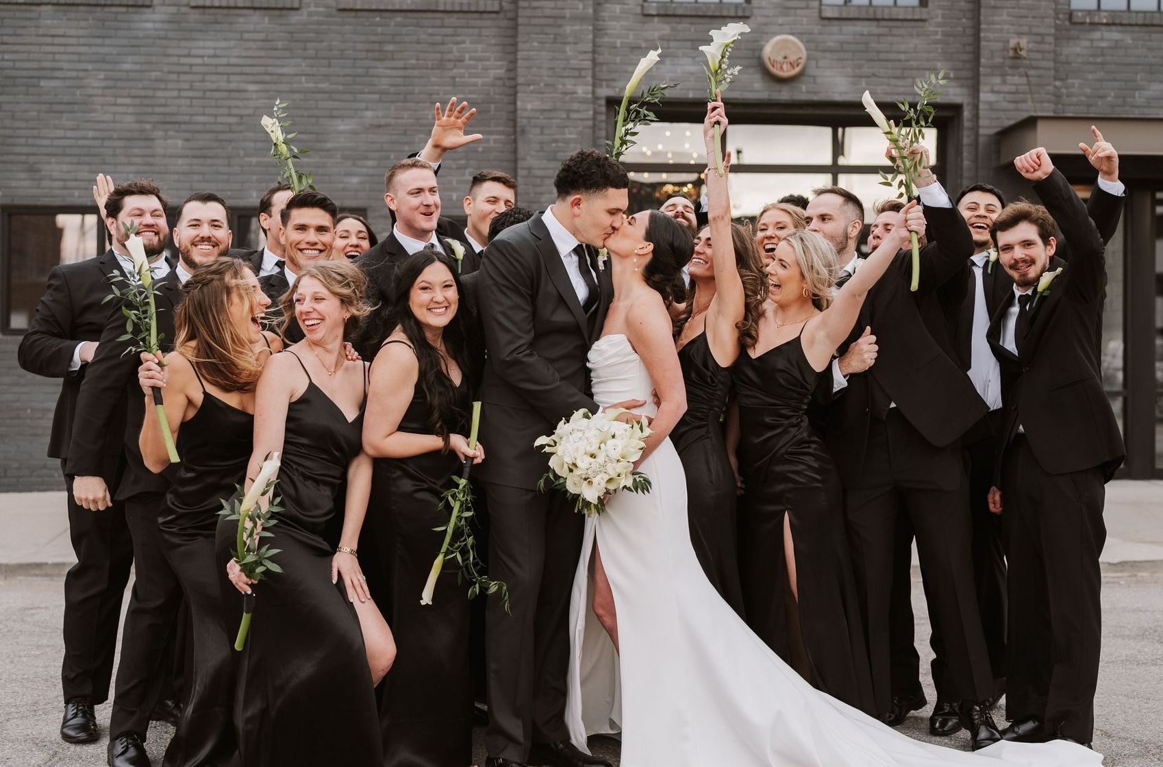 A bride and groom are posing for a picture with their wedding party.