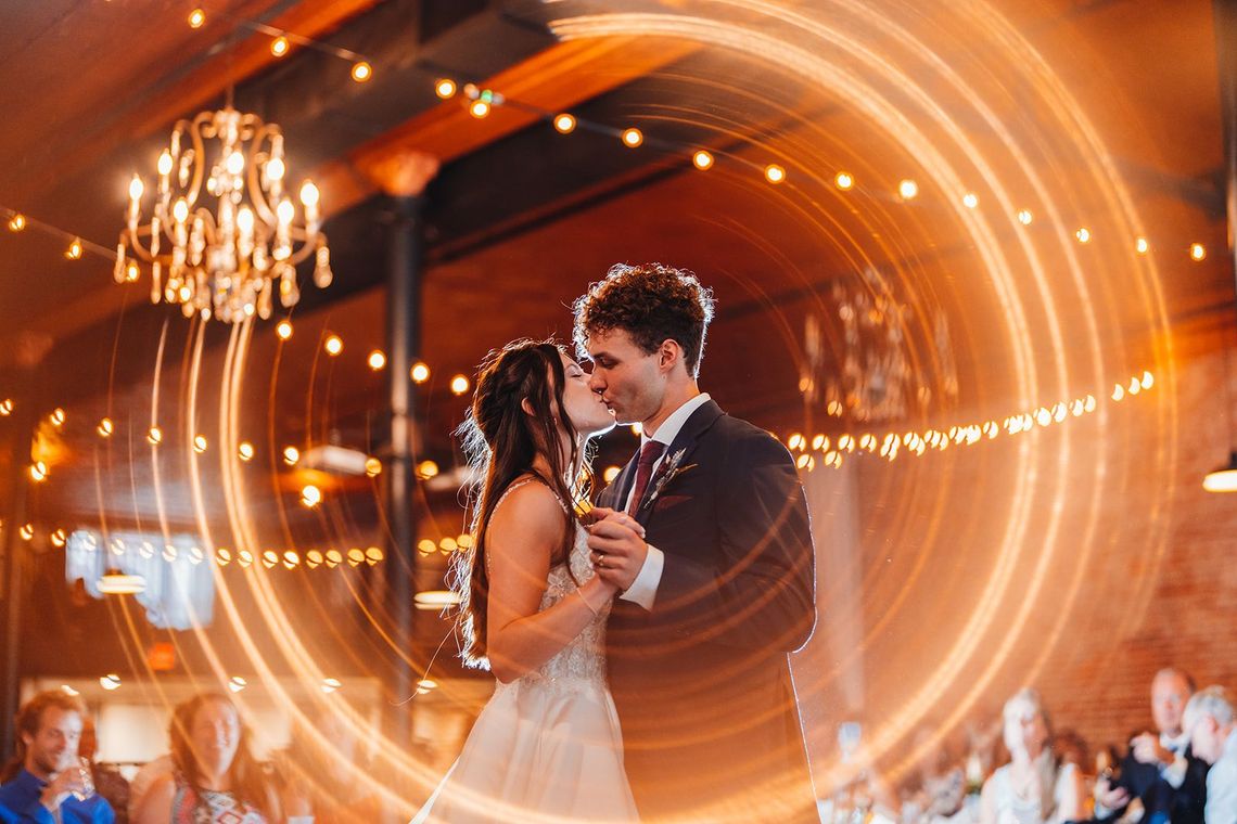 A bride and groom are dancing their first dance at their wedding reception.