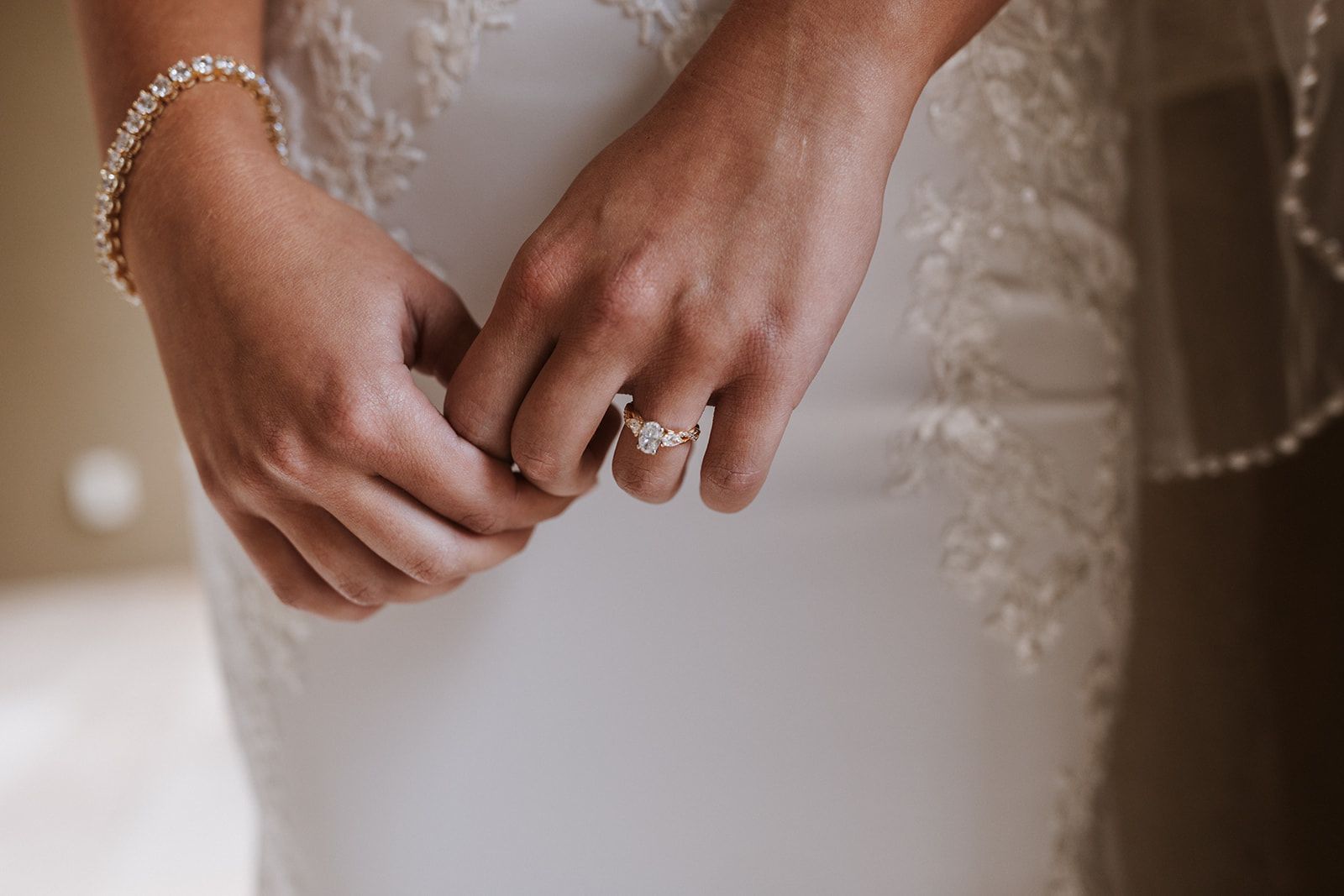 A bride is putting on her wedding ring and bracelet.