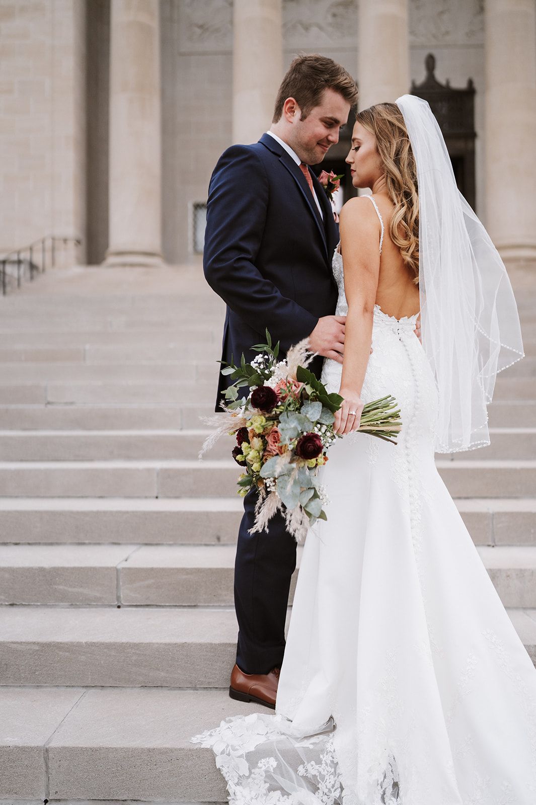 A bride and groom are posing for a picture on a set of stairs.