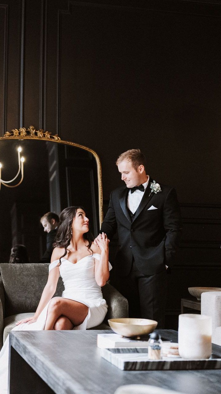 A bride and groom are standing next to each other in front of a mirror.