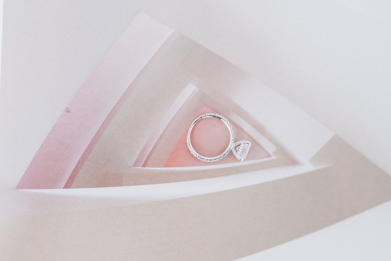 A wedding ring is sitting on top of a pink triangle.