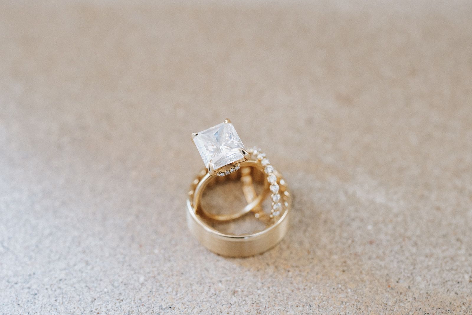 A close up of a wedding ring and engagement ring on a table.
