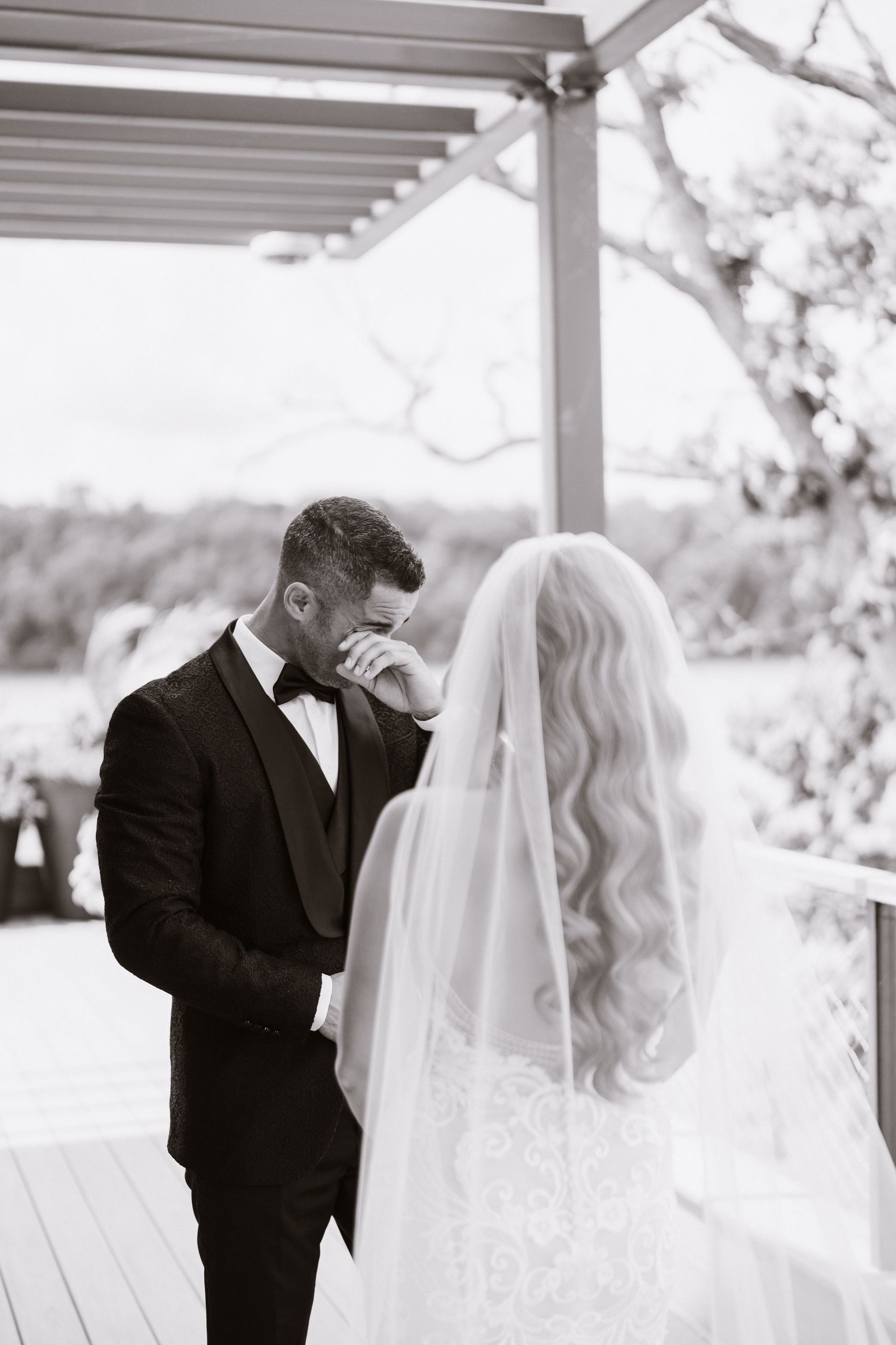 A bride and groom are standing next to each other and the bride is crying.