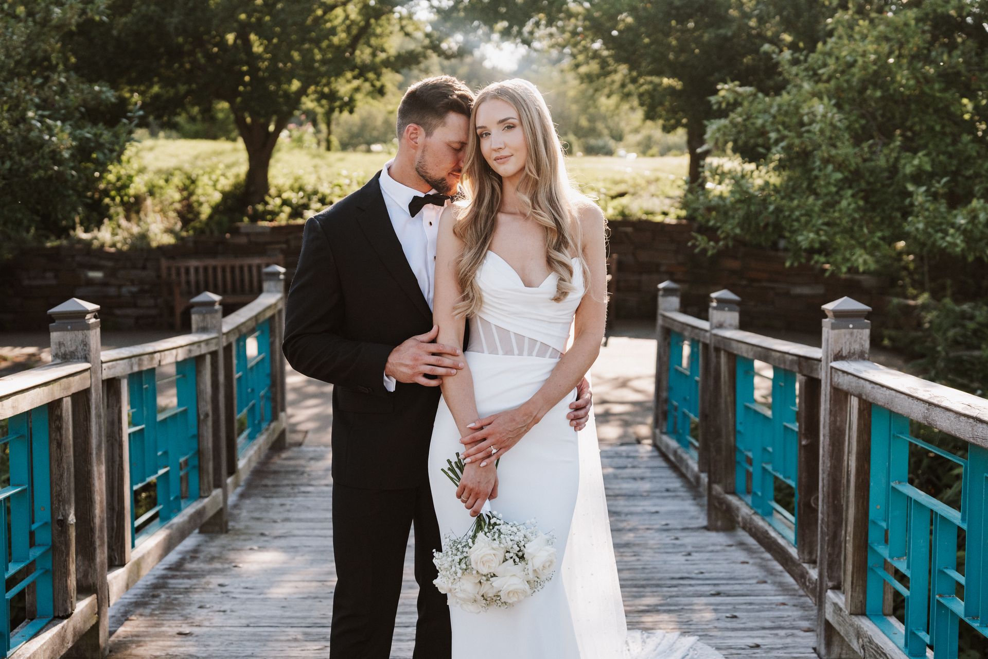 A bride and groom are posing for a picture on a bridge.