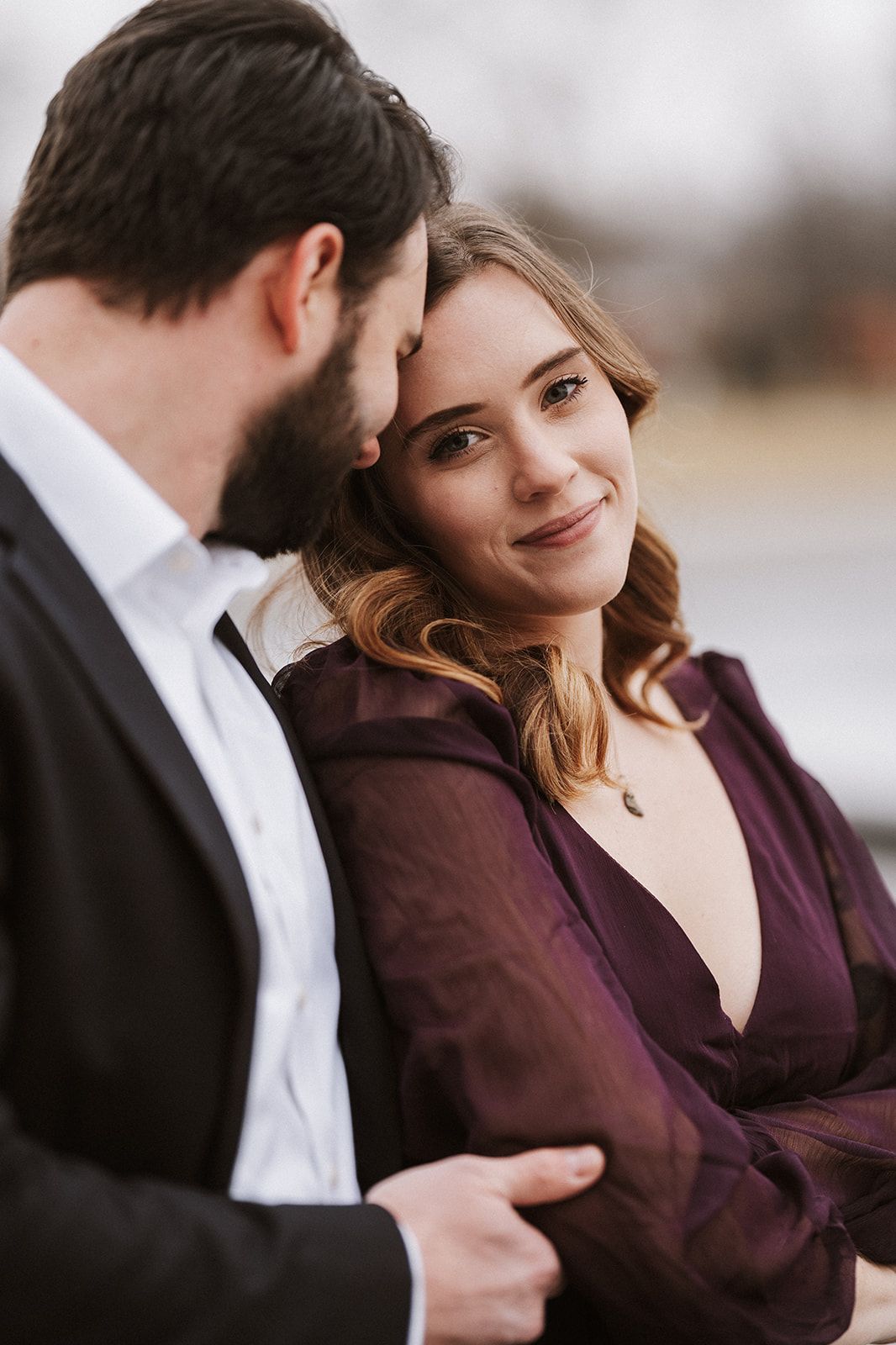 A man and a woman are standing next to each other and the woman is wearing a purple dress.