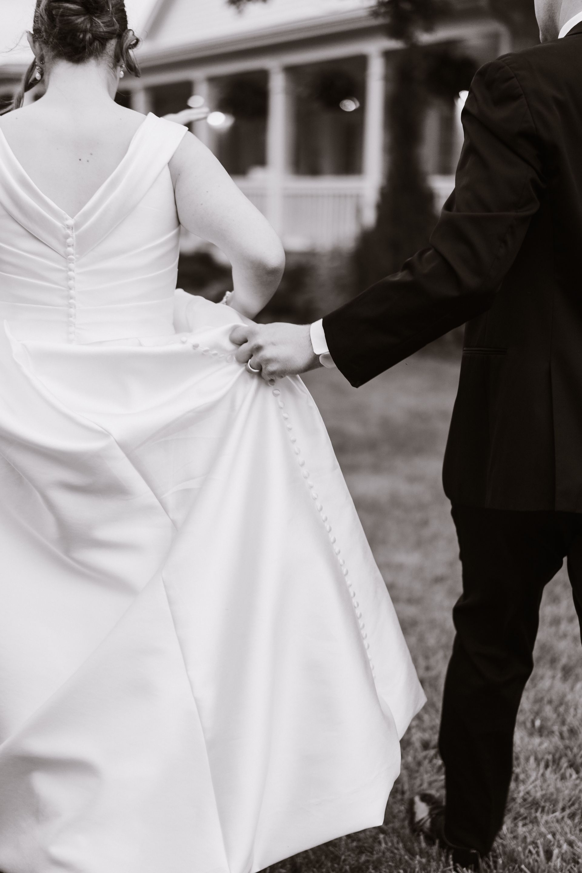 A black and white photo of a bride and groom holding hands.
