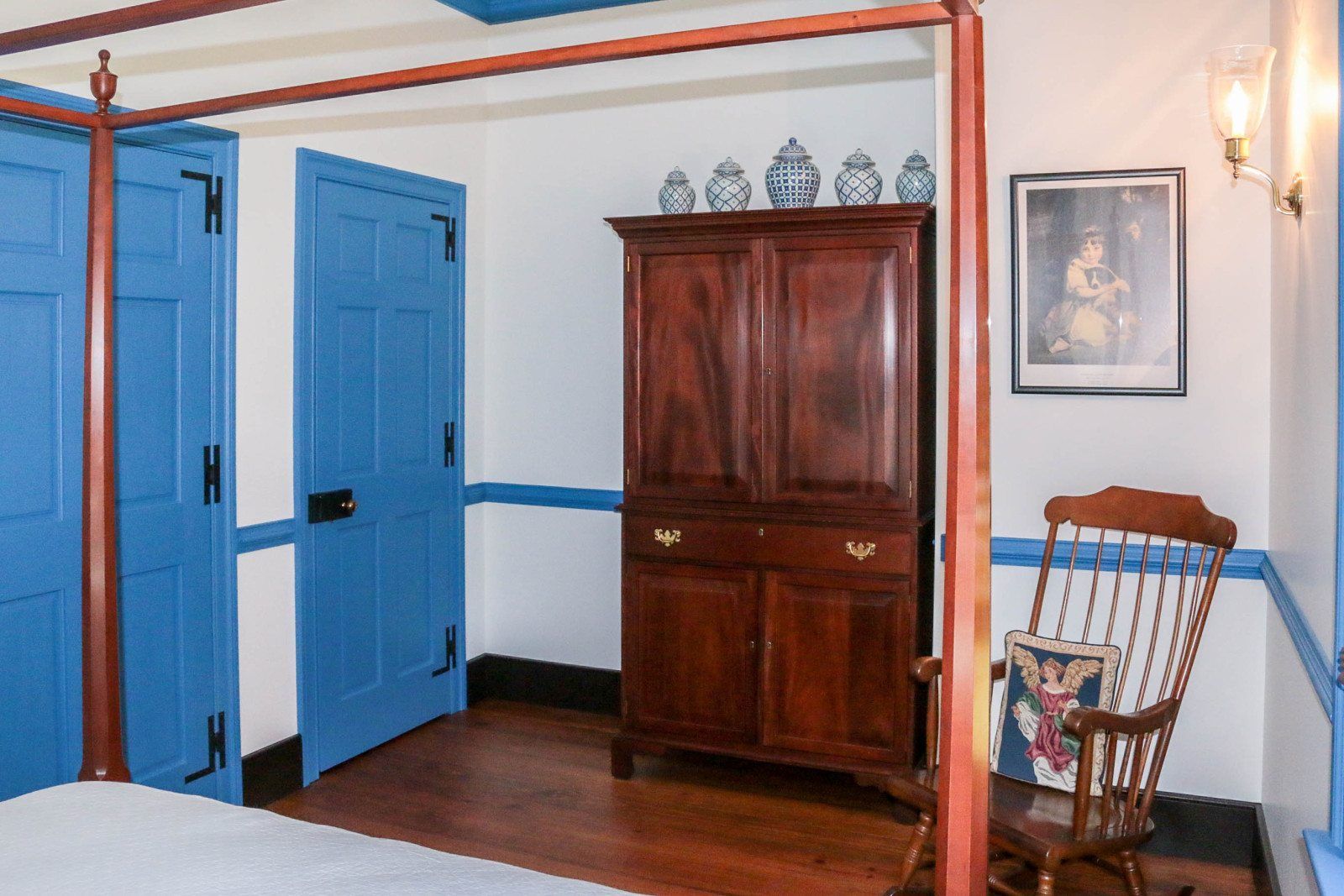 This photo shows a rocking chair, closet and room door as well as a cabinet to store clothes.