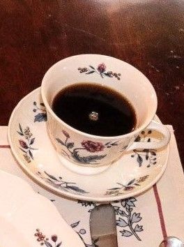 A cup of coffee is on a saucer on a table.