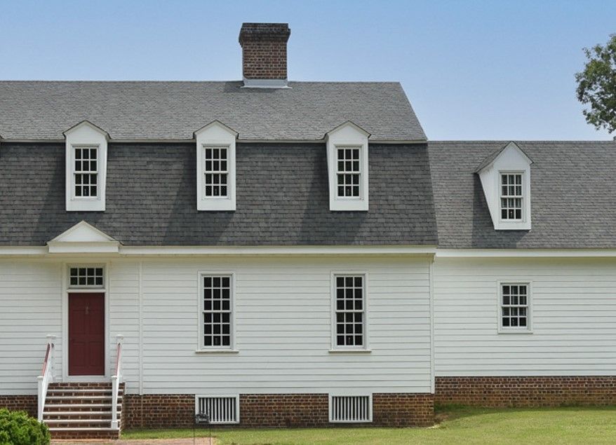 A white house with a gray roof and a red door.