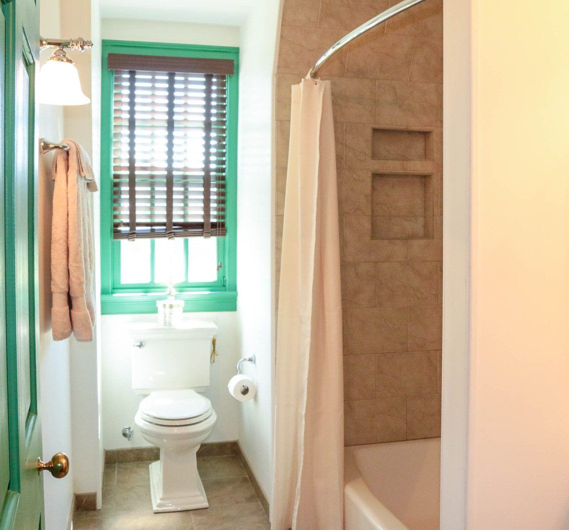 This is a photo of the bathroom in the Green room of the BNB. We see the toilet and shower area.