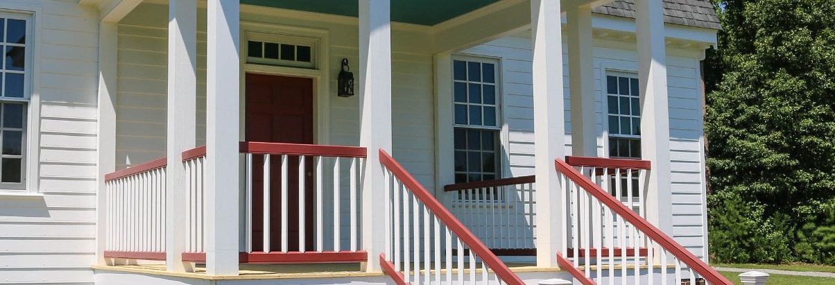 A white house with a porch and red railing