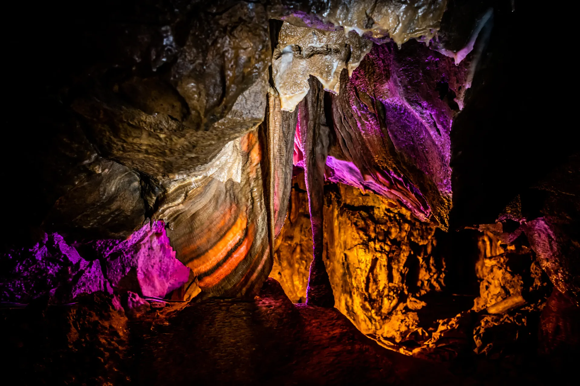 A cave filled with lots of rocks and purple and yellow lights.