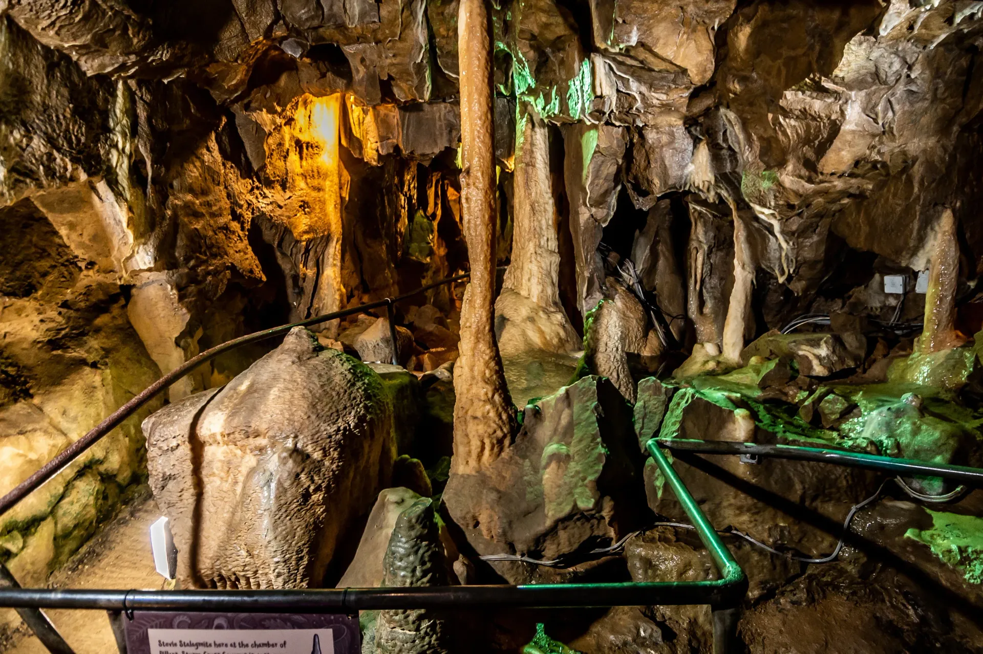A large rock formation in a cave with a sign in the foreground.