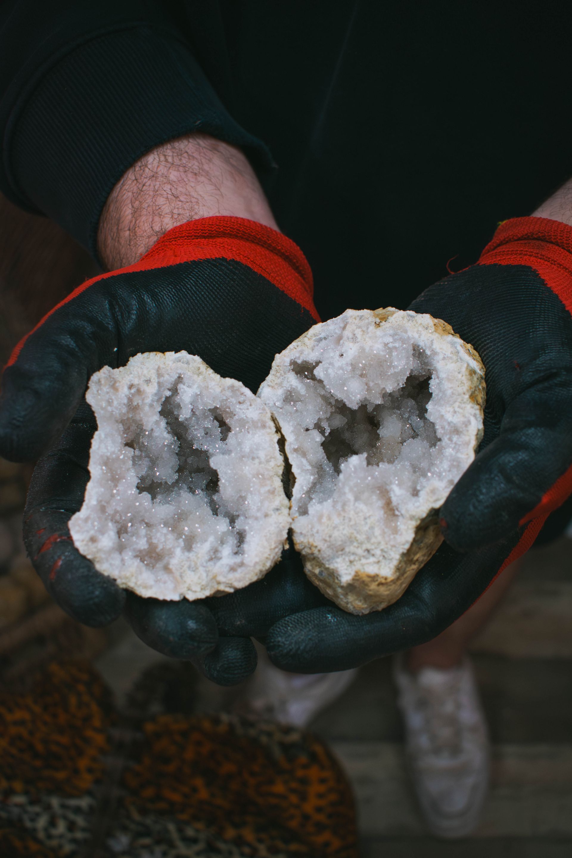 Display of geode stones in baskets and a crate on a wooden table.