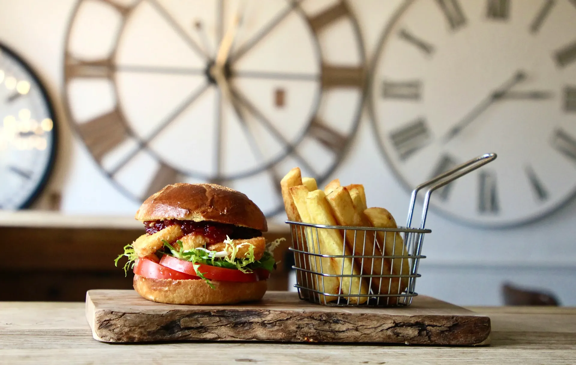 A hamburger and french fries are on a wooden cutting board.