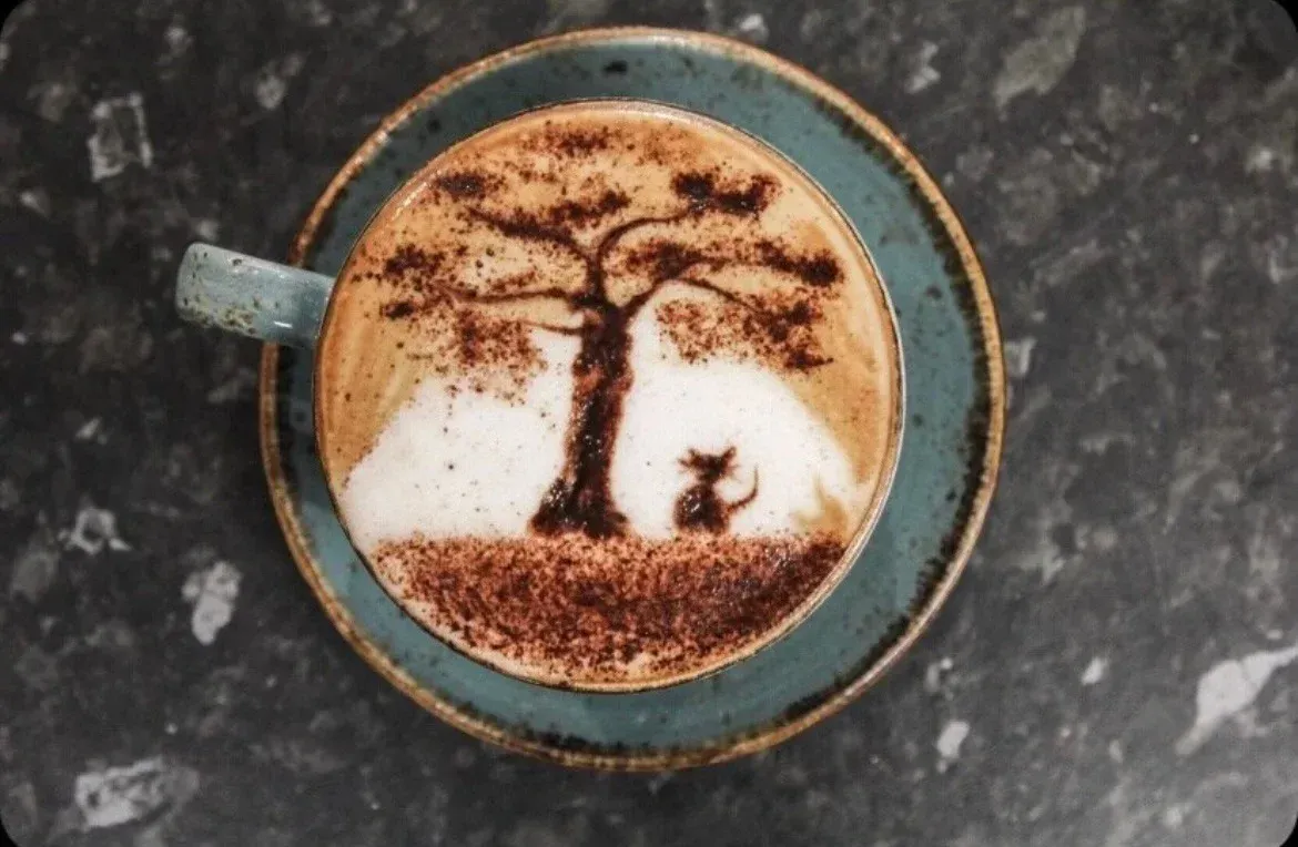 A cup of coffee with a tree and a dog on it