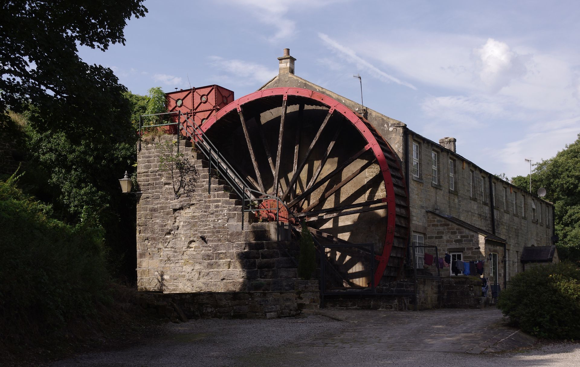A large water wheel in front of a stone building
