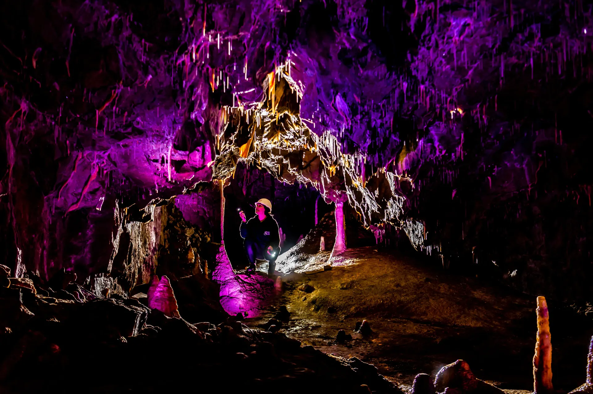 A person is standing in a cave with purple lights.