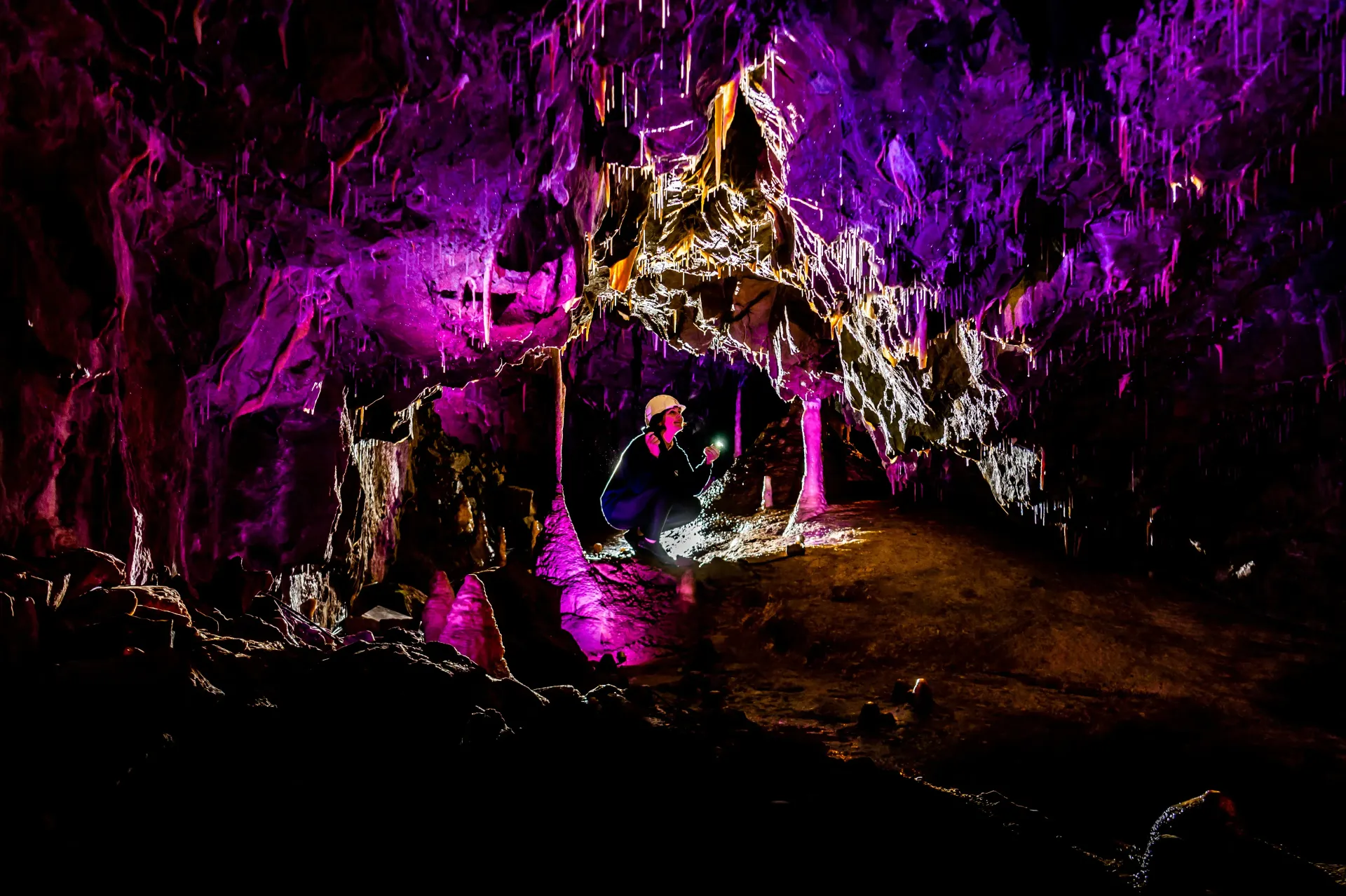 A man is standing in a cave surrounded by purple lights.