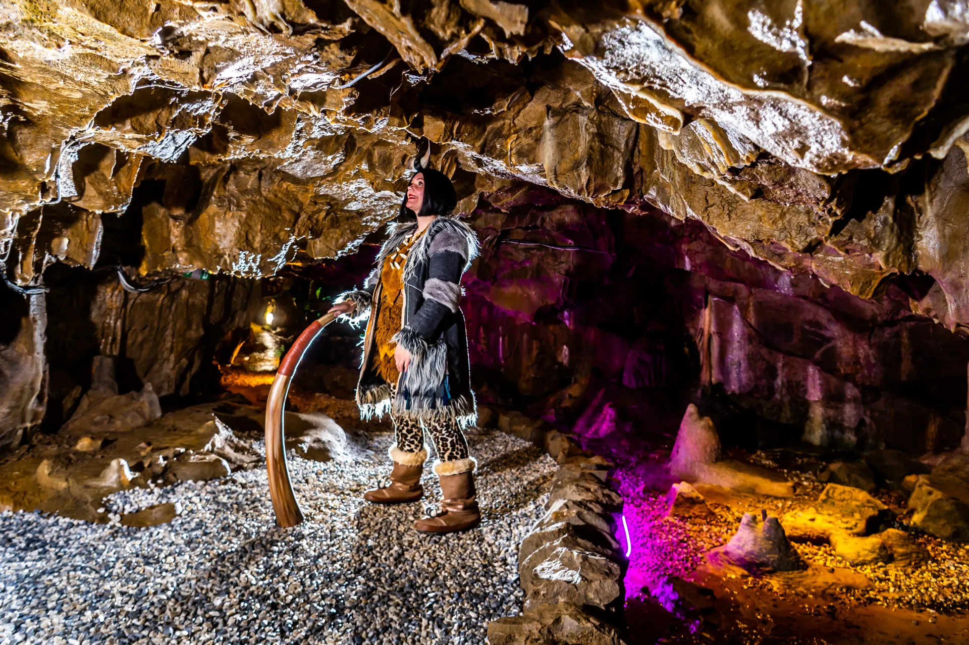 A man is standing in a cave with a purple light coming out of it.