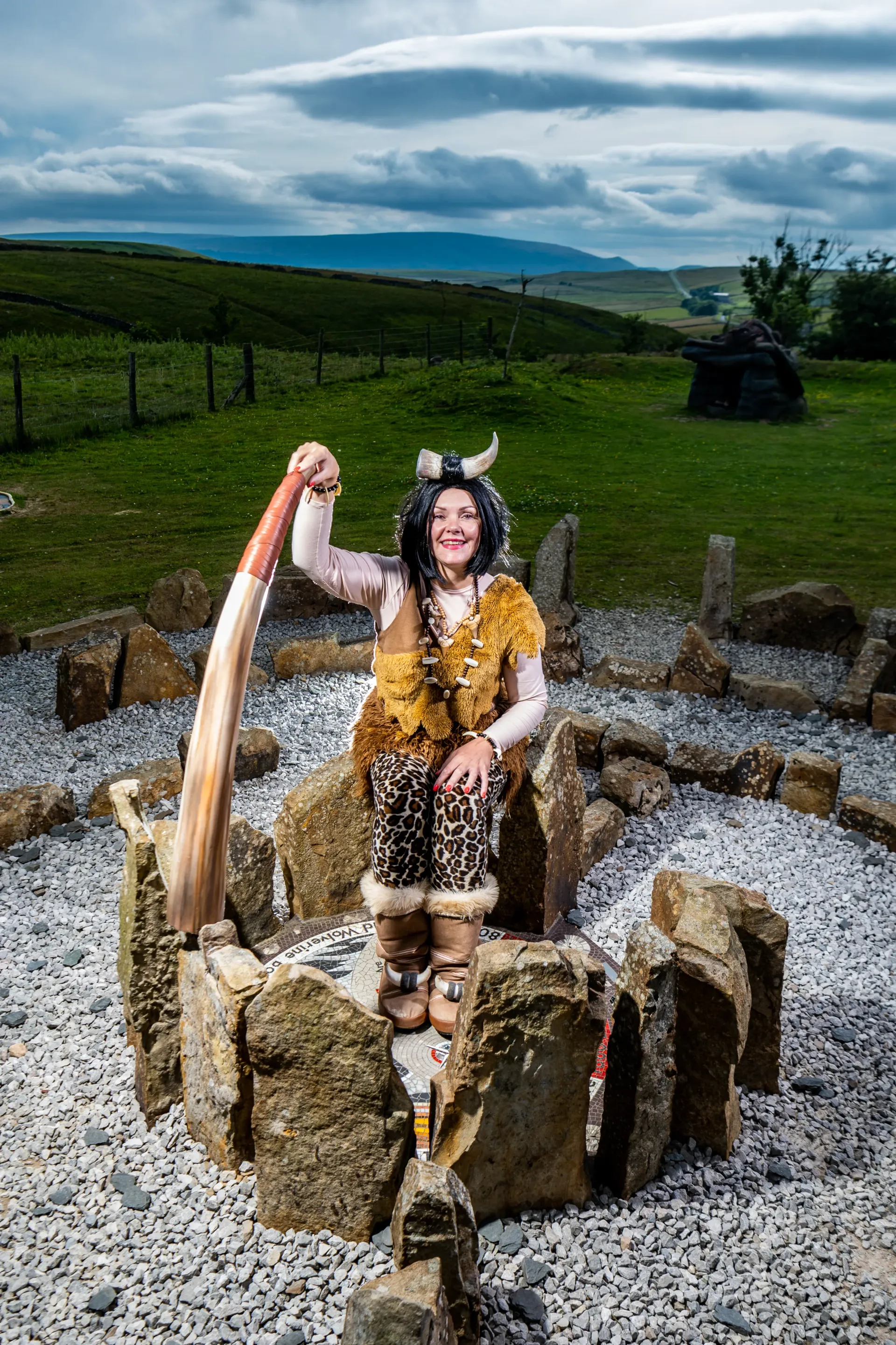 A woman in a viking costume is sitting on a pile of rocks.