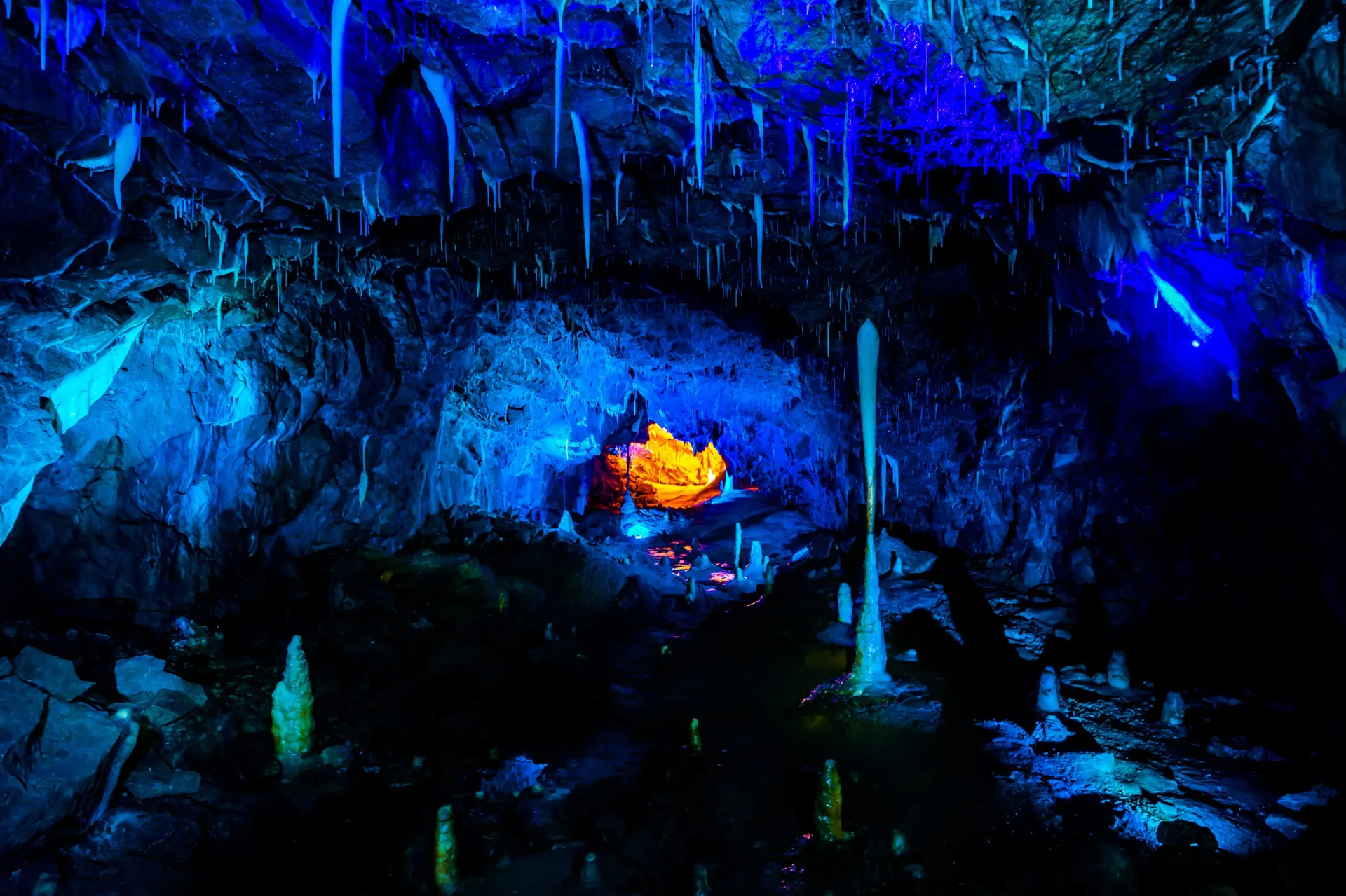 There is a fire in the middle of the cave with blue lights.