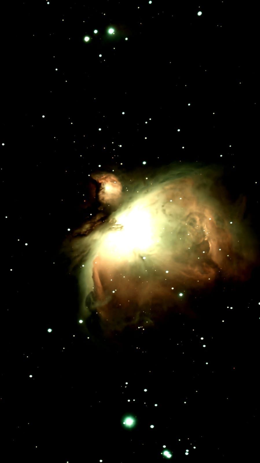 Orion Nebula, a cloud of gas and dust in space, glows with yellow, orange, and green hues, surrounded by stars.