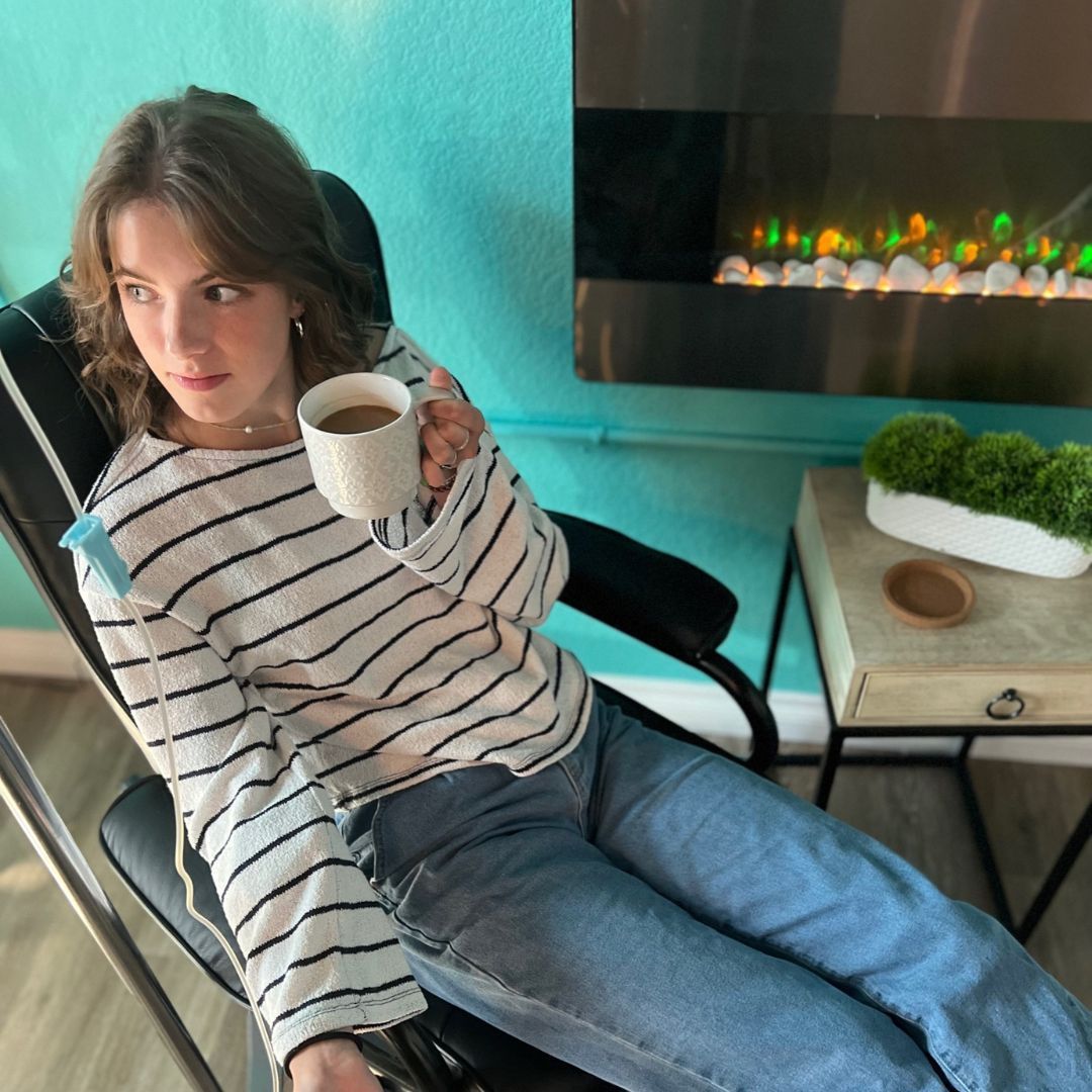 A woman is sitting in a chair holding a cup of coffee