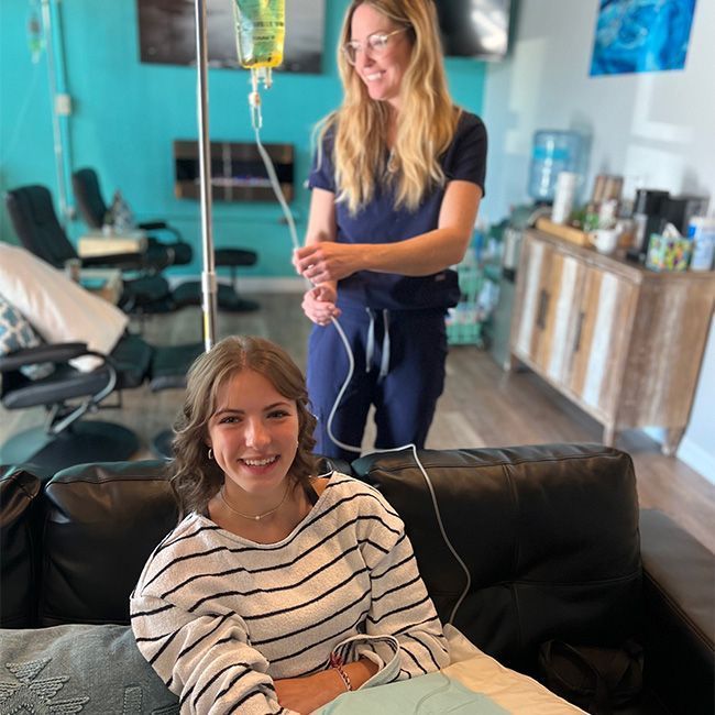 A woman is sitting on a couch with a nurse standing behind her