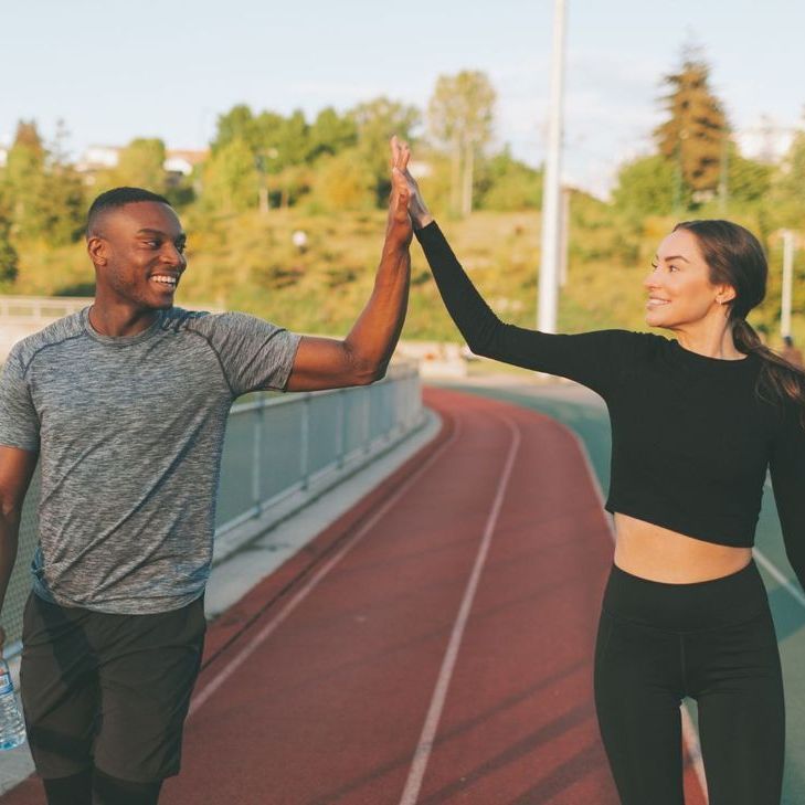 A man and a woman are giving each other a high five on a track