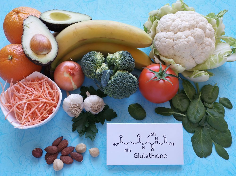 A variety of fruits and vegetables are sitting on a table next to a card that says glutathione.