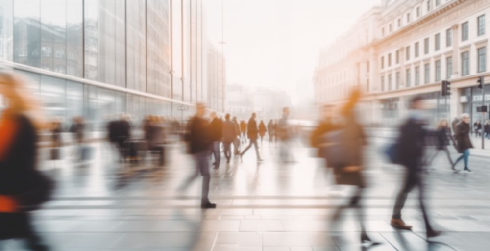 A blurry picture of a crowd of people walking down a city street.