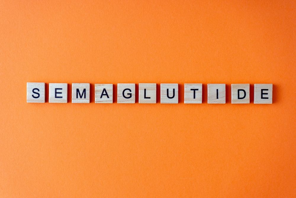 The word semaglutide is written in scrabble tiles on an orange background.