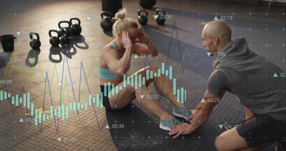 A man is helping a woman do sit ups in a gym.