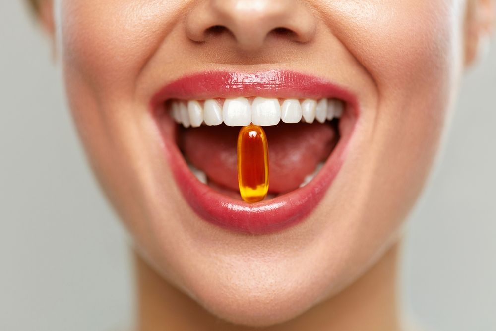 A woman is taking a pill out of her mouth.