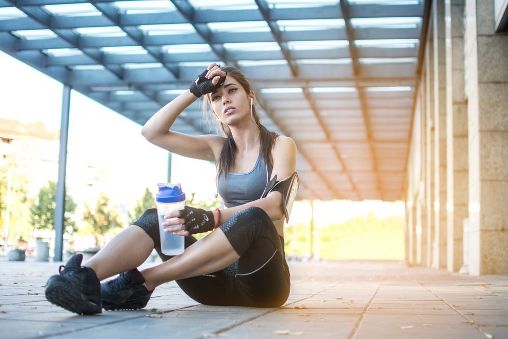 A woman is sitting on the ground with a bottle of water.