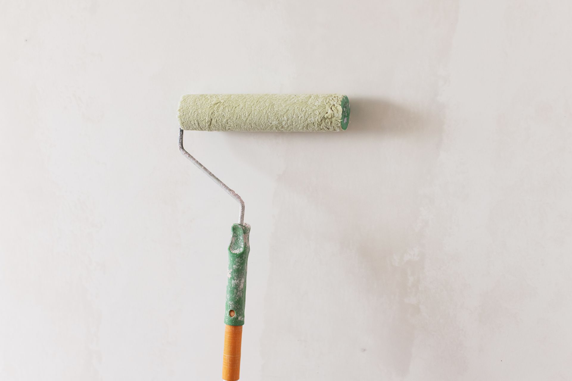 A man is painting a wall with a paint roller.