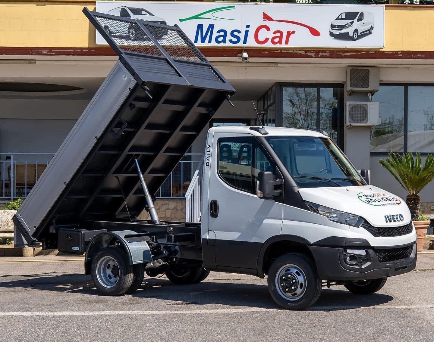 Un autocarro con cassone ribaltabile è parcheggiato davanti a un negozio di automobili Masi